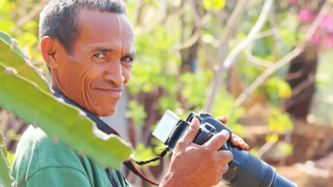 Karen Edyvane Faustino Mauloko da Cunha holds a telephoto camera