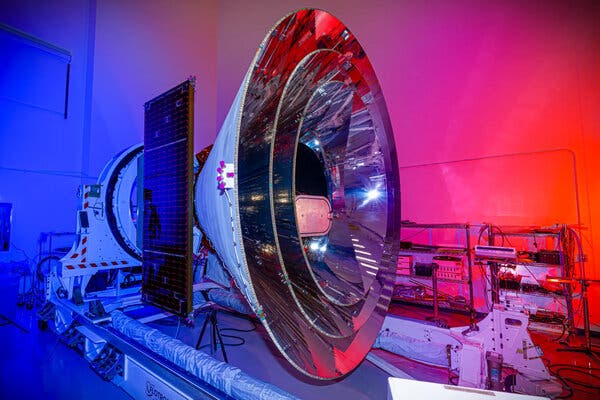 A large metal device made up of three concentric cones sits in a blue- and red-lit testing room.